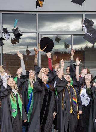 Graduates in regalia throwing their caps into the air