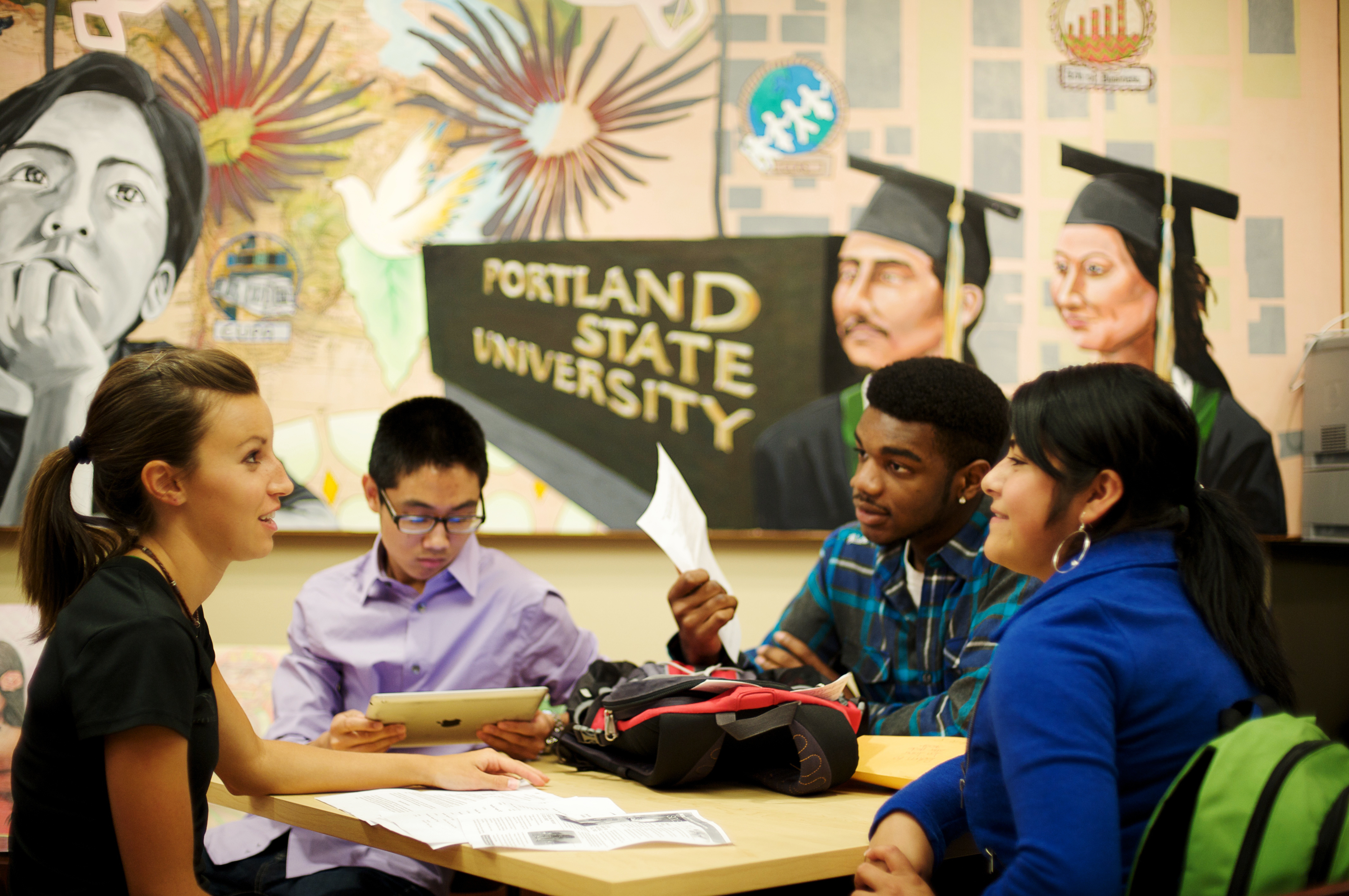 Group of diverse college students sitting at a table and having a conversation.