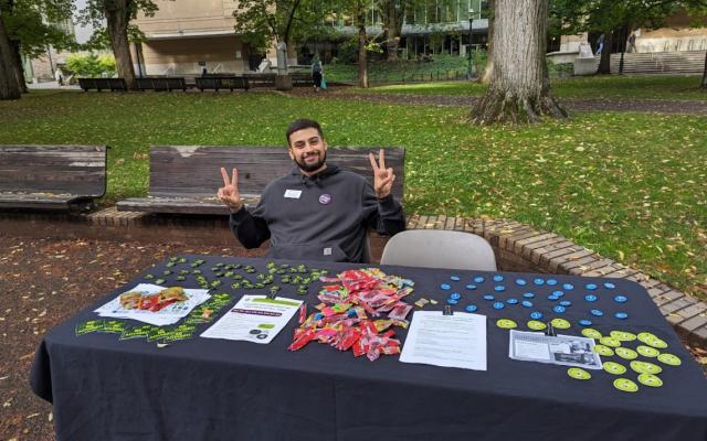 staff member sitting outside at a table with resource materials and PSU swag